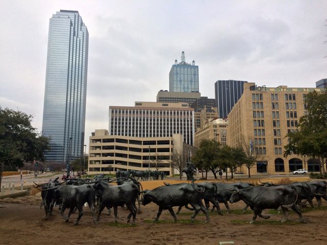 Pioneer Plaza, a bronze cattle drive in front of glass skyscrapers