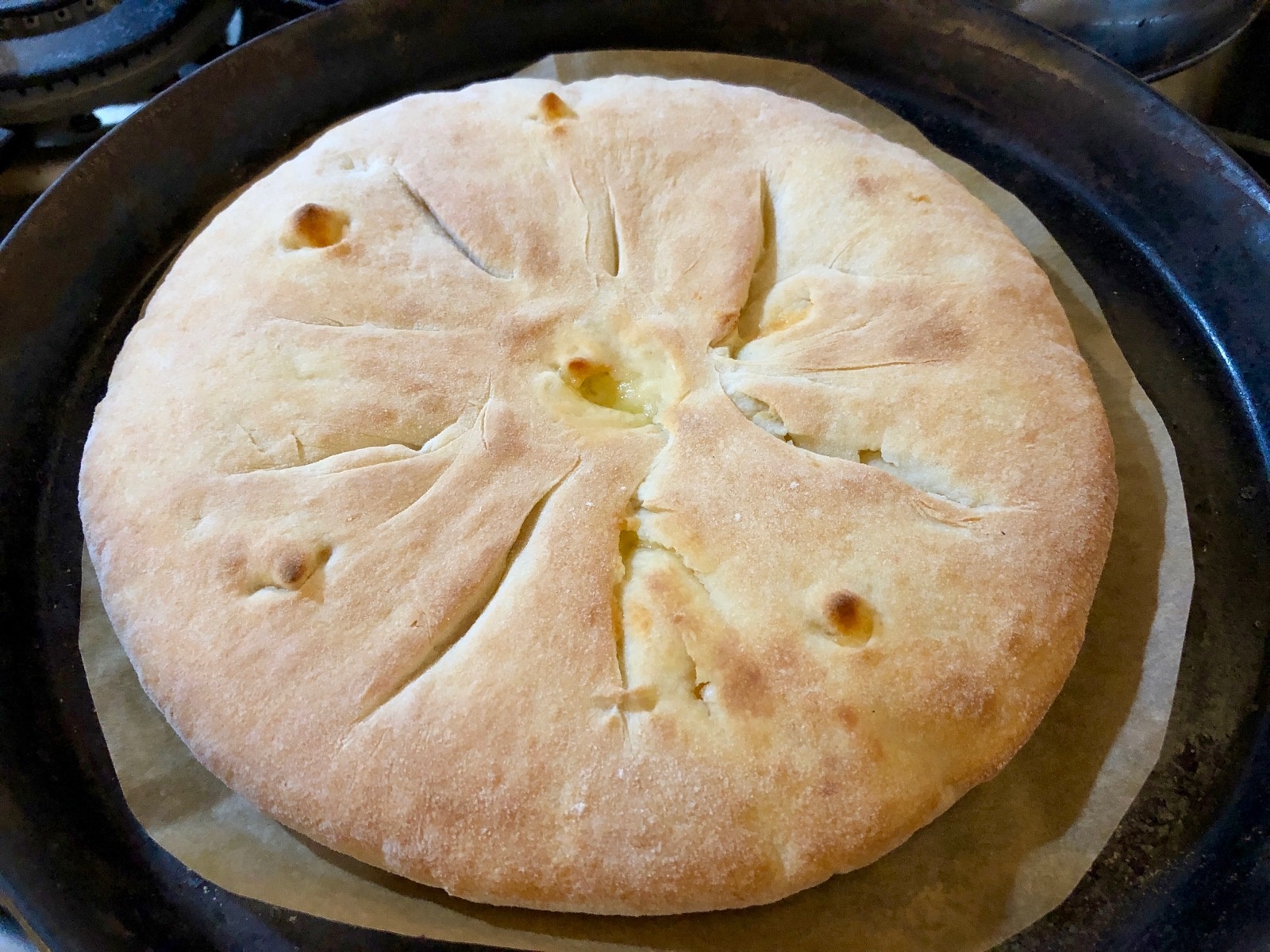 Bild von einem runden goldbraun gebackenem Megruli Khachapuri (bisschen wie eine mit Käse gefüllte runde Calzone)Fotografiert und gebacken von Henry James